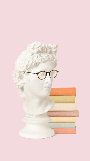A white bust of a man with glasses next to a stack of books