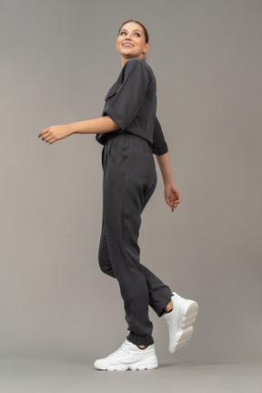 Side view of a smiling walking young woman in a jumpsuit