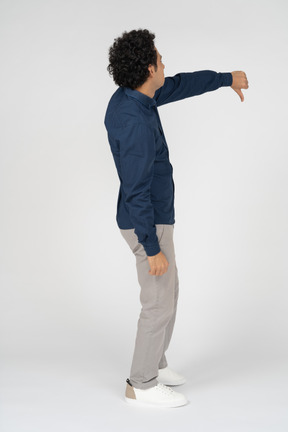 Side view of a man in casual clothes showing thumb down