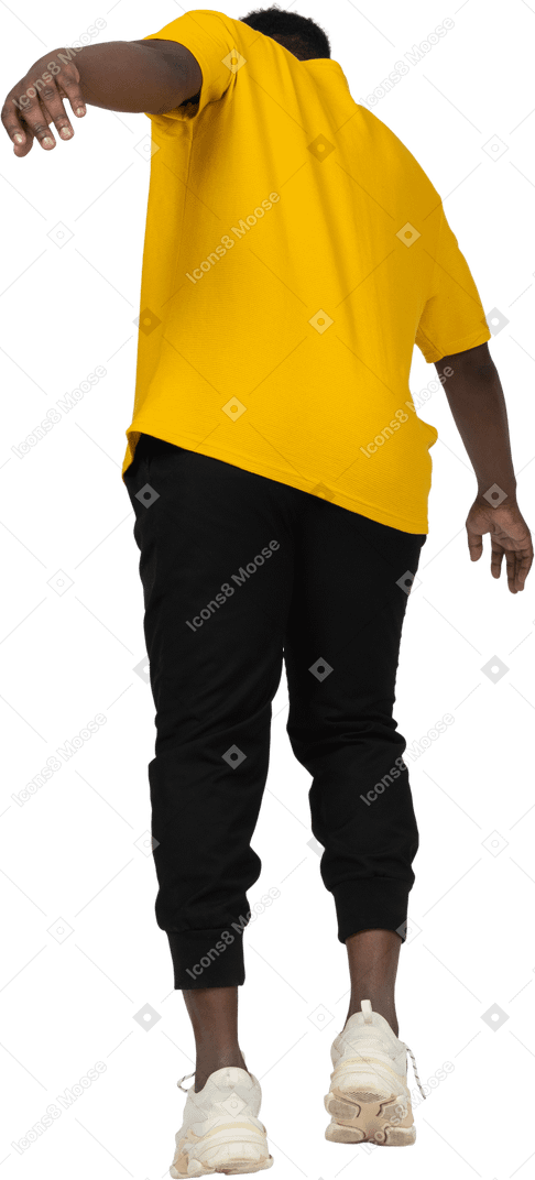 Vista posterior de un joven de piel oscura con camiseta amarilla inclinado hacia adelante y estirando el brazo