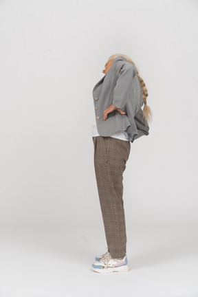 Side view of an old lady in suit stretching