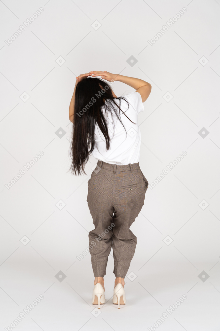 Vista posteriore di una giovane donna spaventata in calzoni che tocca la sua testa