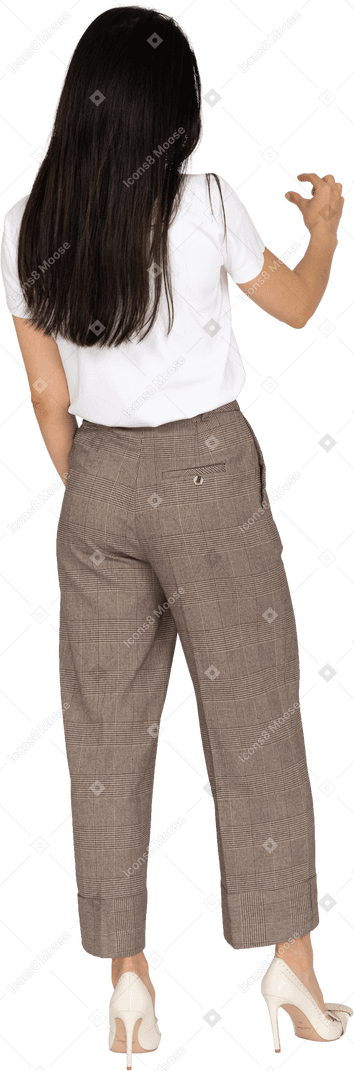 Vista posterior de tres cuartos de una mujer joven con pantalones y camiseta blanca que muestra el tamaño de algo