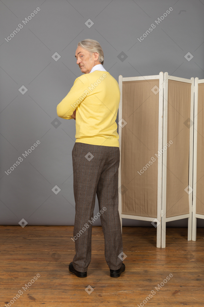 Three-quarter back view of an offended old man crossing hands