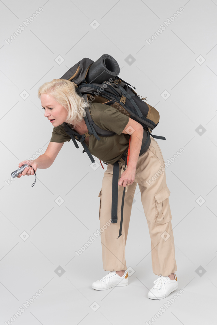 Carrying backpack mature female tourist using dictaphone