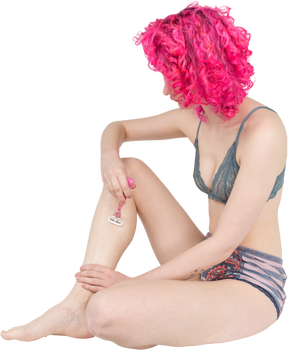 Девочка-подросток с вьющимися розовыми волосами бреет ноги