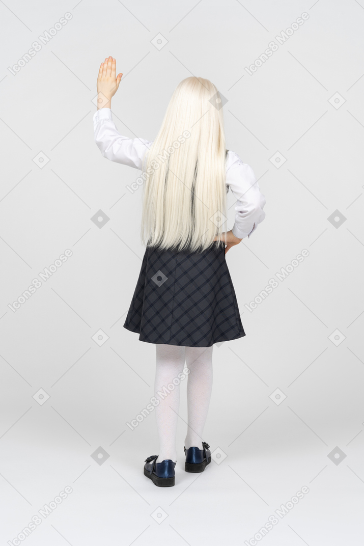 Back view of a schoolgirl raising her hand