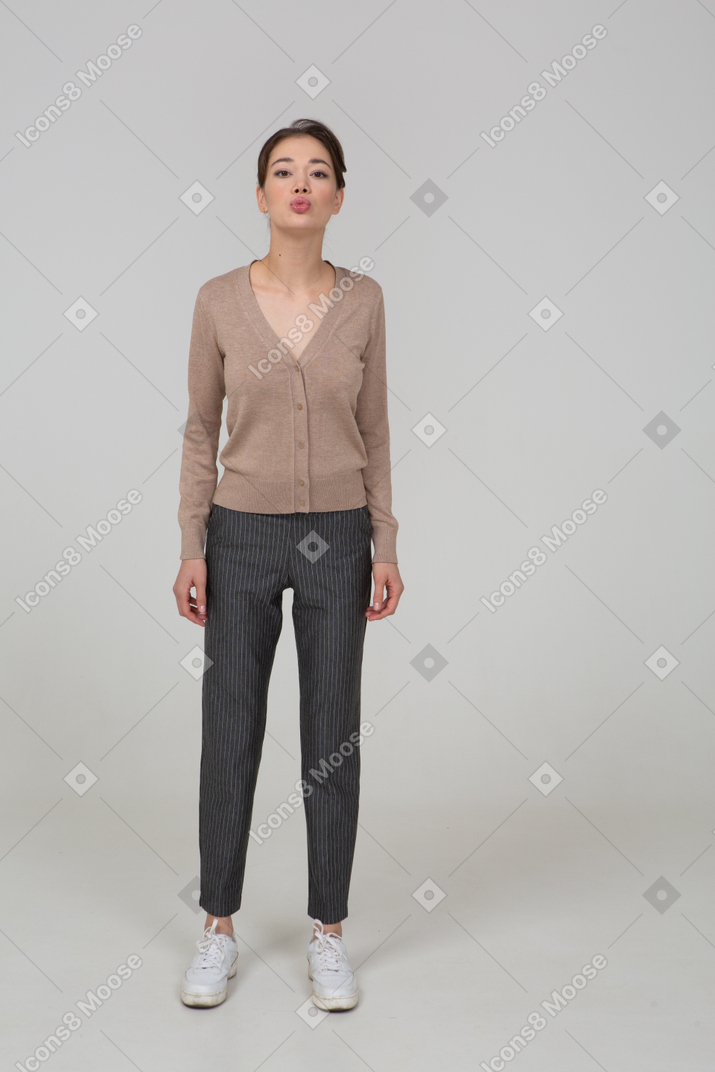 Vista frontale di una giovane donna imbronciata in pullover e pantaloni