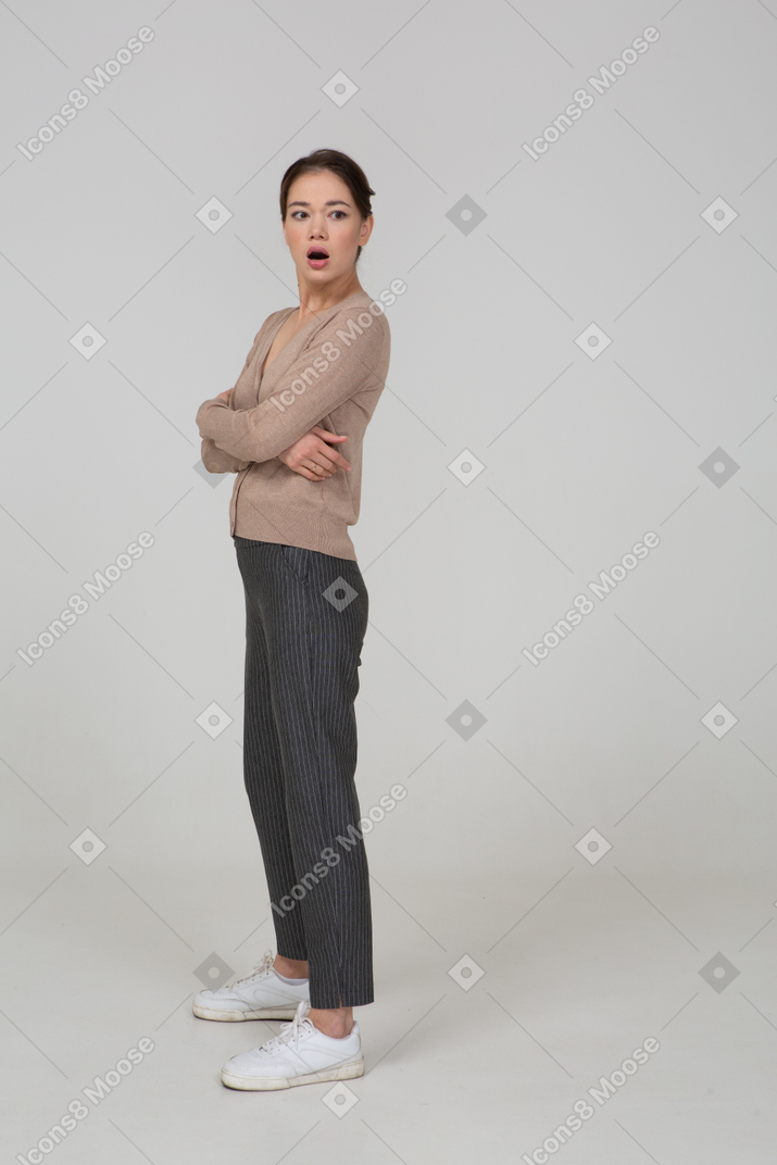 Vista di tre quarti di una giovane donna stupita in maglione beige che attraversa le mani