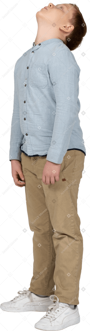 Vista lateral de un niño con ropa informal mirando hacia arriba