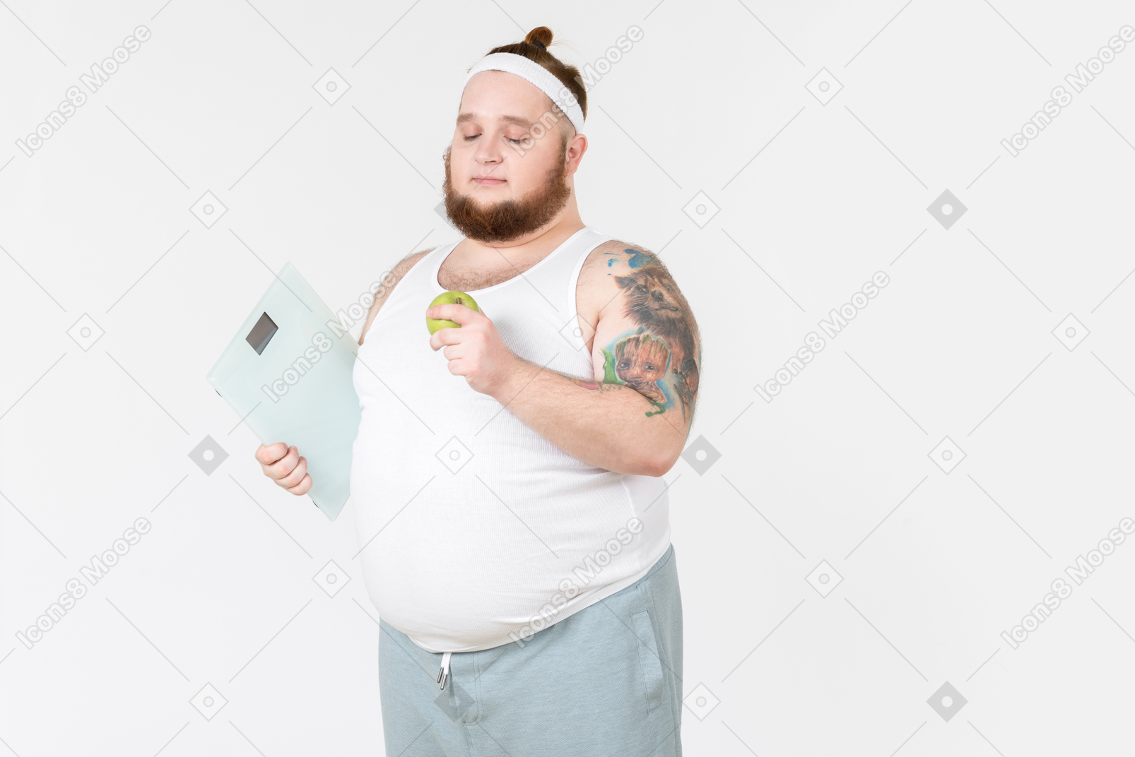 Большой парень в спортивной одежде держит цифровые веса и серьезно смотрит на яблоко, которое держит