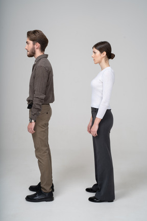 Vista lateral de um jovem casal com roupas de escritório pressionando os lábios