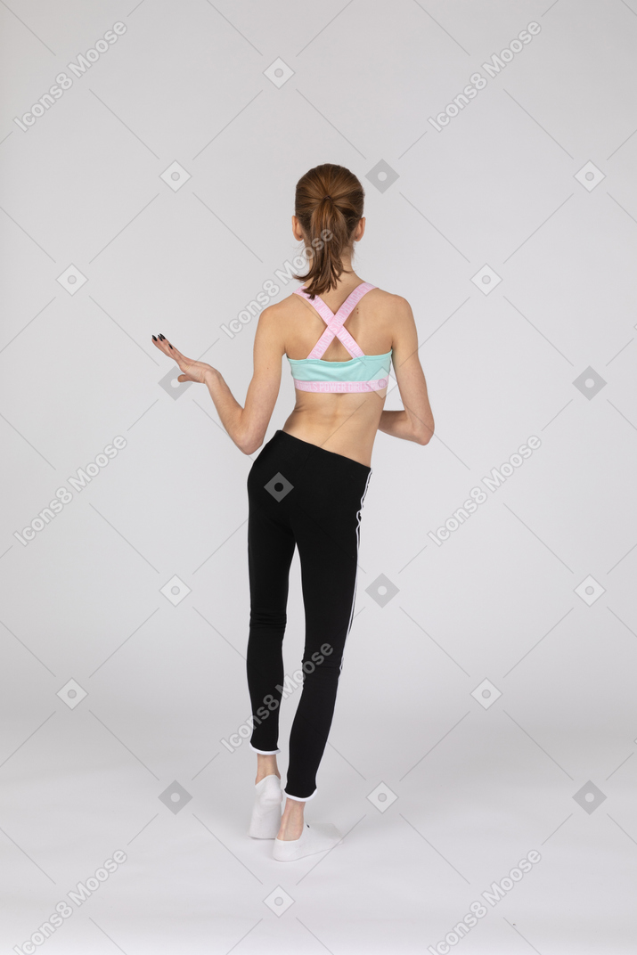 Vista posterior de una jovencita en ropa deportiva bailando mientras gesticula