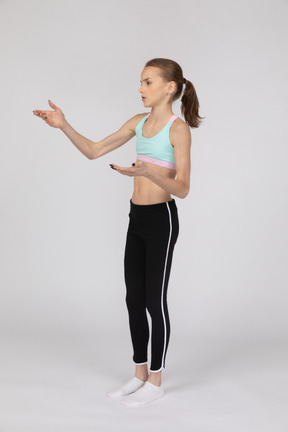 Three-quarter view of a teen girl in sportswear raising hand and arguing