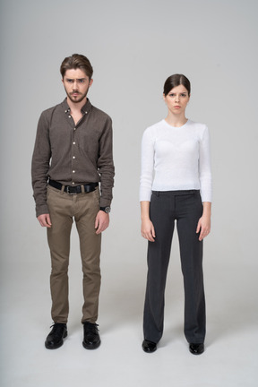 Front view of a young couple in office clothing standing still & knitting brows