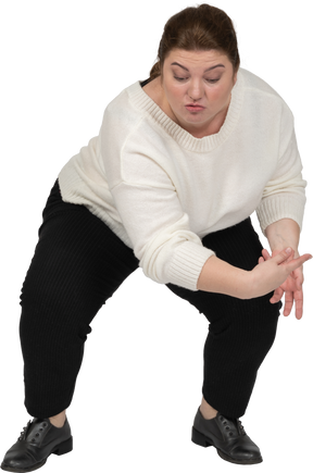 Front view of a plus size woman in casual clothes squatting