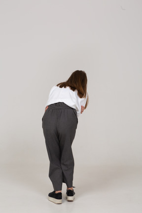 Back view of a young lady in office clothing with stomach ache bending down