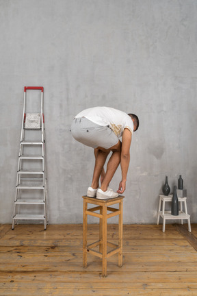 Man standing on chair and bending down