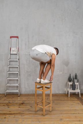 Homme debout sur une chaise et se penchant