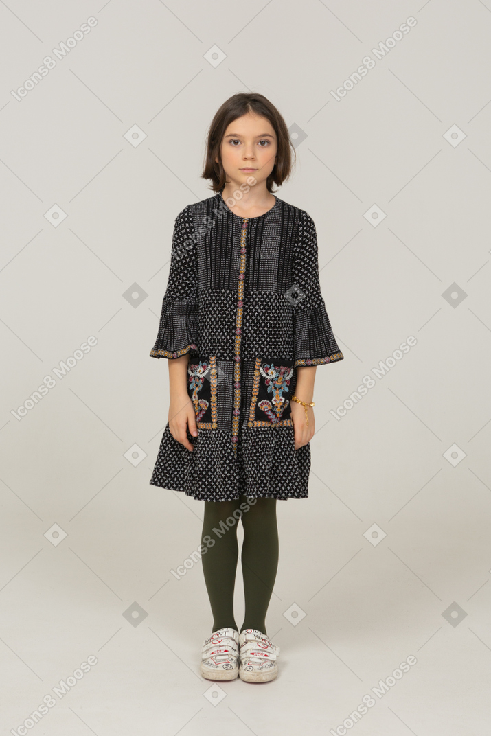 Vista frontale di una bambina vestita che guarda l'obbiettivo