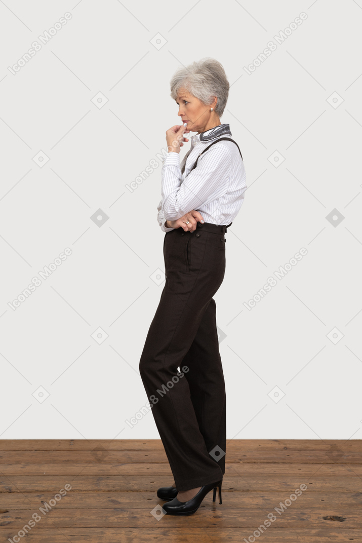Side view of a thoughtful old lady in office clothing touching face