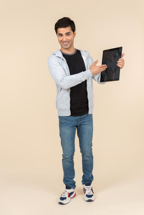 Young caucasian man pointing at a digital tablet he's holding