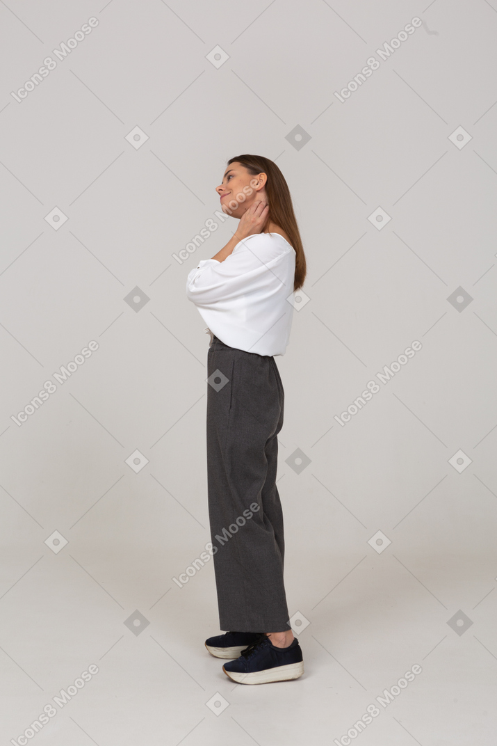 Vista lateral de una joven en ropa de oficina inclinando la cabeza y tocando el cuello