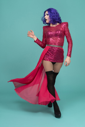 Front view of a drag queen in pink flowing skirt walking confidently