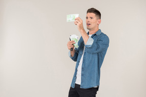 Young stand-up comic looking carefully at banknotes he's holding