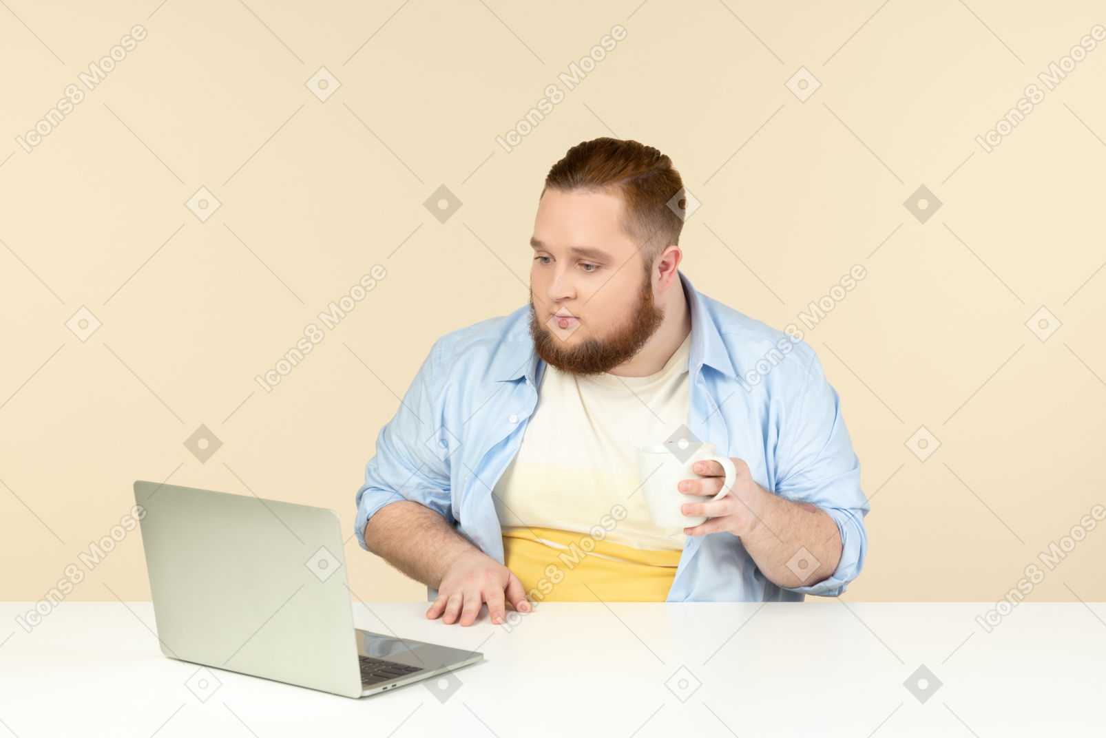 Surprised young overweight sitting in front of laptop and having tea