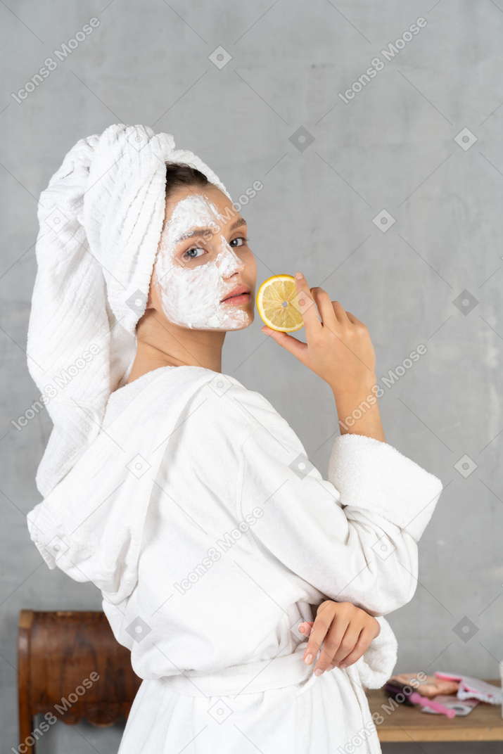 Back view of a woman in bathrobe holding a lemon