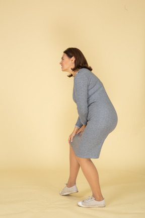 Vista laterale di una donna in abito grigio che tocca il ginocchio