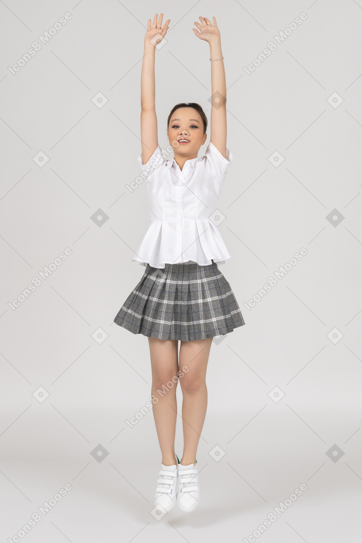 A cheerful asian girl stretching up in a jump