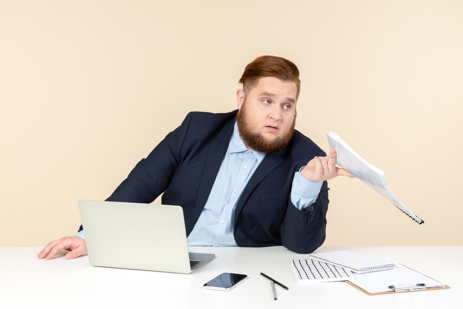 Young overweight office worker sitting at the desk and holding papers