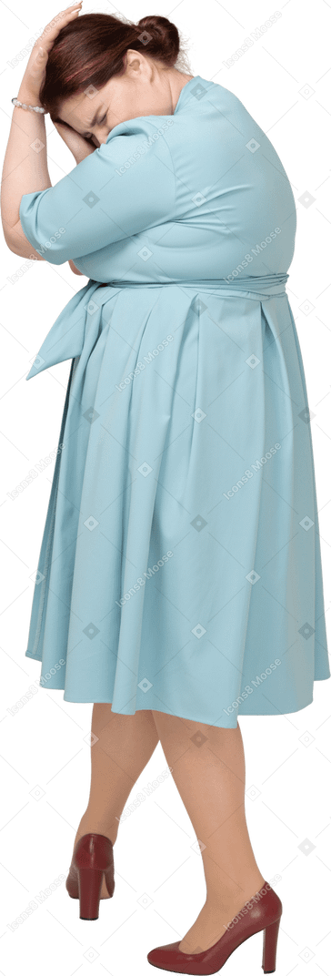 Side view of a woman in blue dress touching head