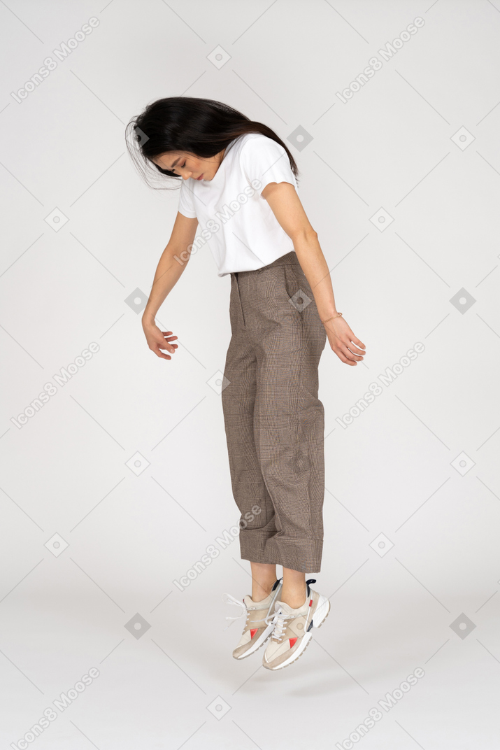 Vista de três quartos de uma jovem saltitante de calça e camiseta