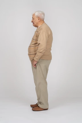 Side view of an old man in casual clothes standing with hands in pockets