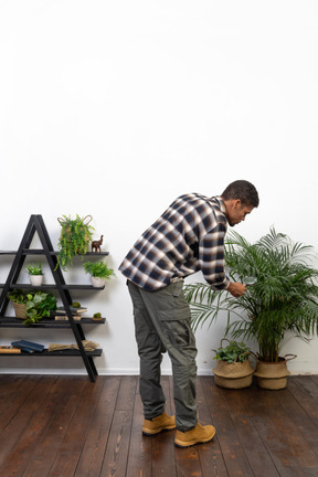 Three-quarter back view of a tourist leaning forward searching something with magnifying glass