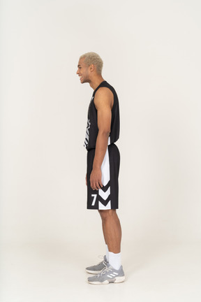 Side view of a laughing young male basketball player standing still