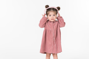 戴着耳机的粉红色连衣裙的小女孩