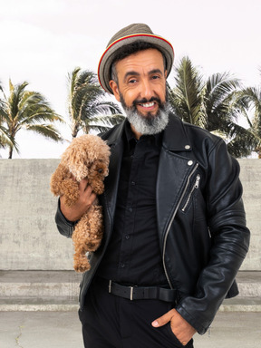 A man in a leather jacket holding a little dog