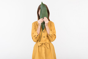 Young woman closing face with green leaf