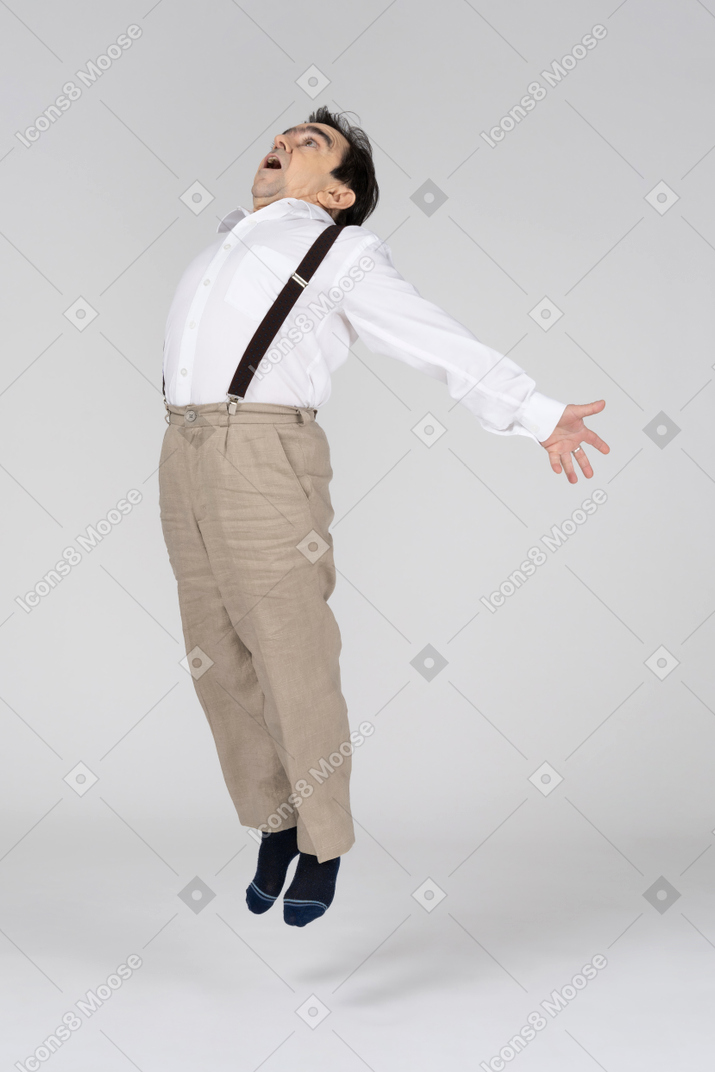 Hombre de mediana edad saltando con los brazos extendidos