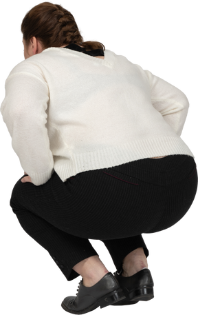 Вид сзади на сидящую на корточках женщину больших размеров в повседневной одежде