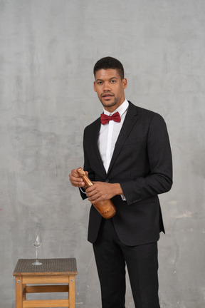 Homem com roupa formal em pé com uma taça de champanhe na mão