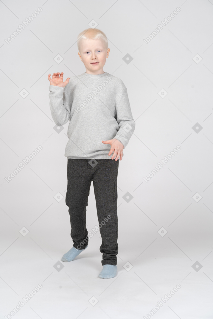 Маленький мальчик стоит и делает жесты руками