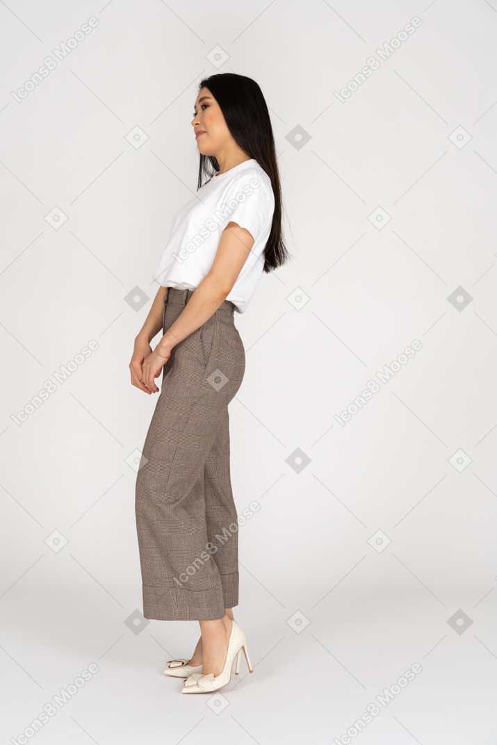 Side view of a confused young lady in breeches and t-shirt holding hands together