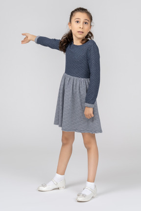 A little girl in a blue dress pointing at something