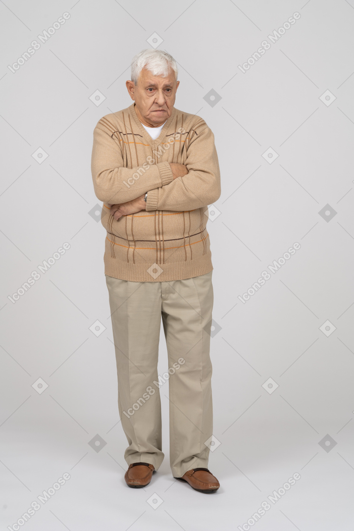 Front view of an old man in casual clothes standing with crossed arms and looking at camera