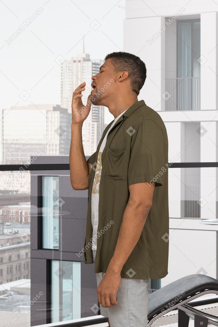 A man standing on a balcony and yawning